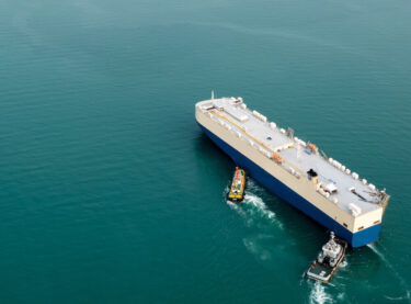 tug boats pushing a shipping container