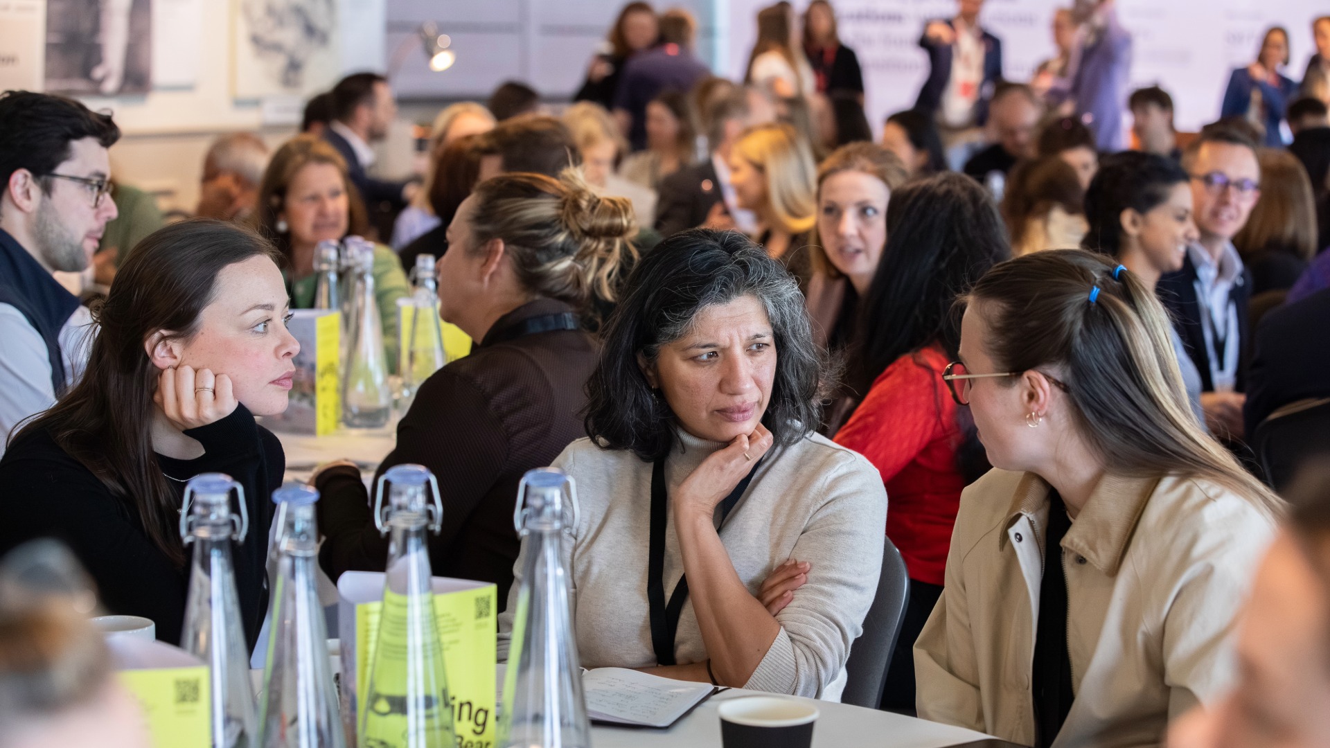 Anthesis Activator Summit: Show Me the Performance Three women sat talking at a table in a packed conference room