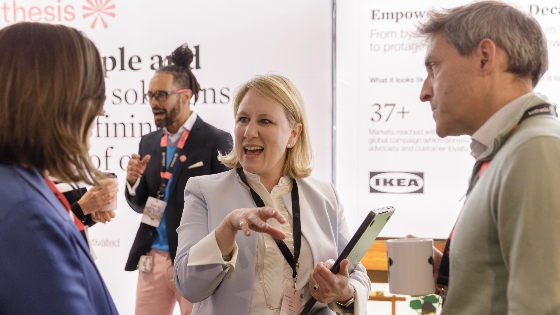 Anthesis Activator Summit: Show Me the Performance Two women and a man talking with people in the background