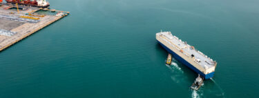tug boats pushing a shipping container